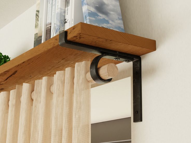 a wooden shelf with magazines on top of it next to a curtain rod and window