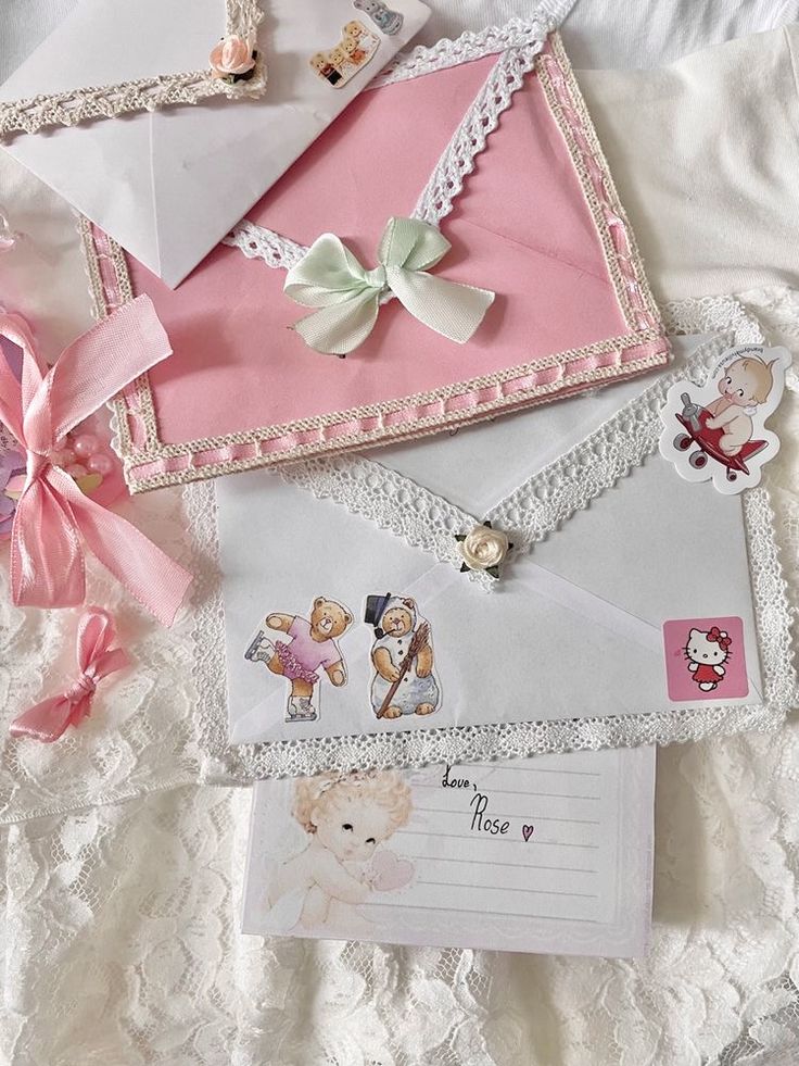 several envelopes are laid out on a bed with pink bows and ribbons around them