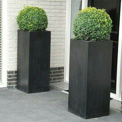 two tall black planters sitting on the side of a building