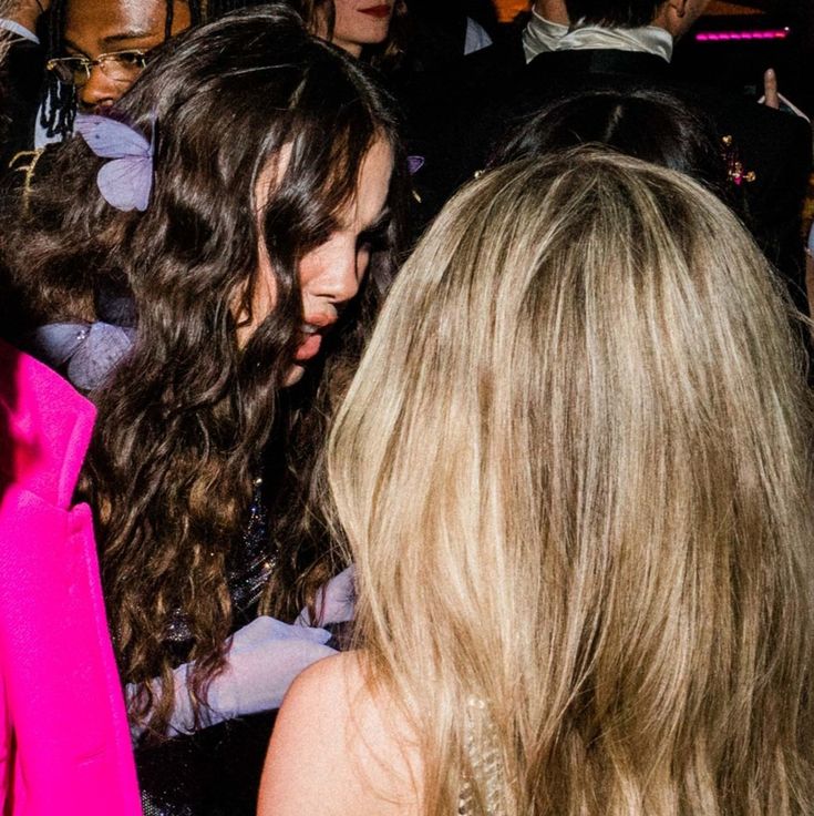 a group of women standing next to each other in a room with people around them