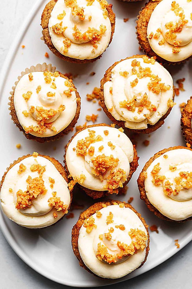 several cupcakes with white frosting and sprinkles on a plate