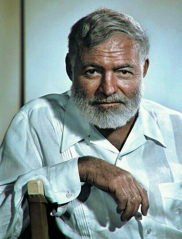 an old man with a white beard sitting in a chair and looking at the camera