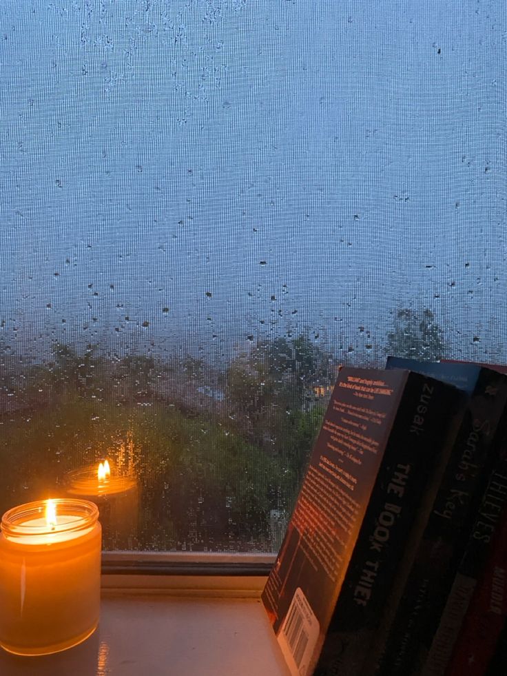 a candle sitting on top of a window sill next to books