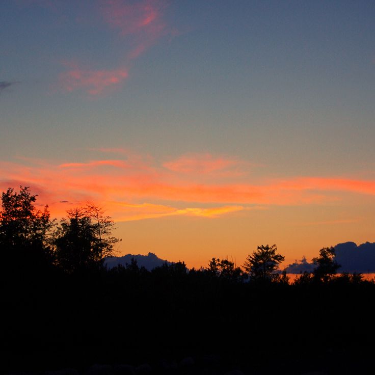 the sun is setting over some trees and mountains