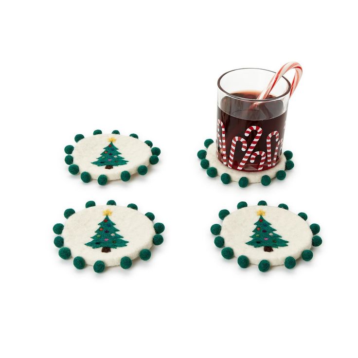 three decorated cookies next to a cup with candy canes on it and a glass filled with liquid