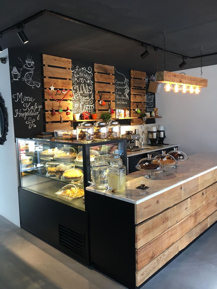 a bakery with lots of food on display behind the counter and chalk writing on the wall