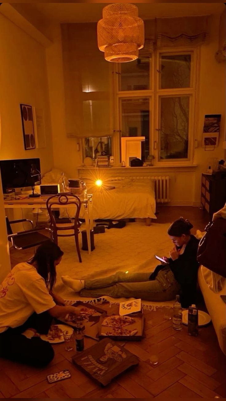 two people sitting on the floor in a living room at night with their laptops open