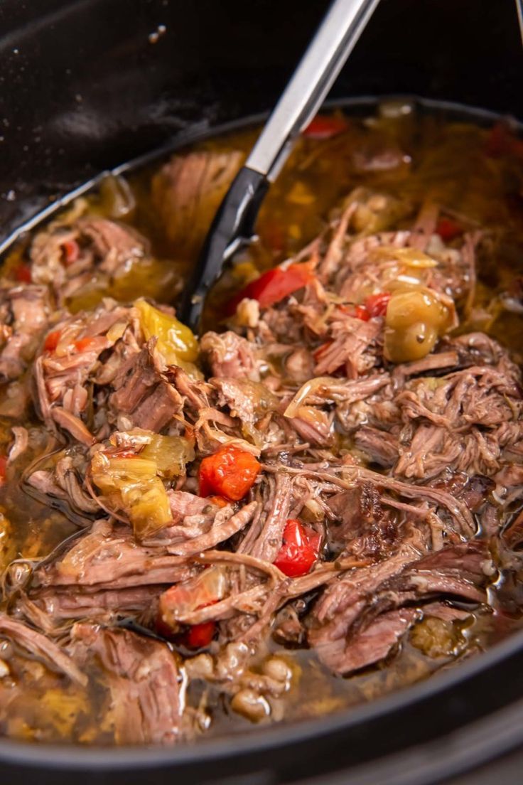 a pot filled with meat and vegetables being stirred by a ladle in the slow cooker