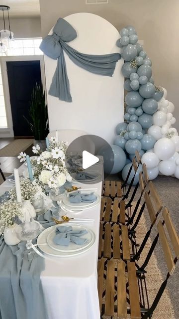 the table is set with blue and white balloons, silver place settings, and flowers