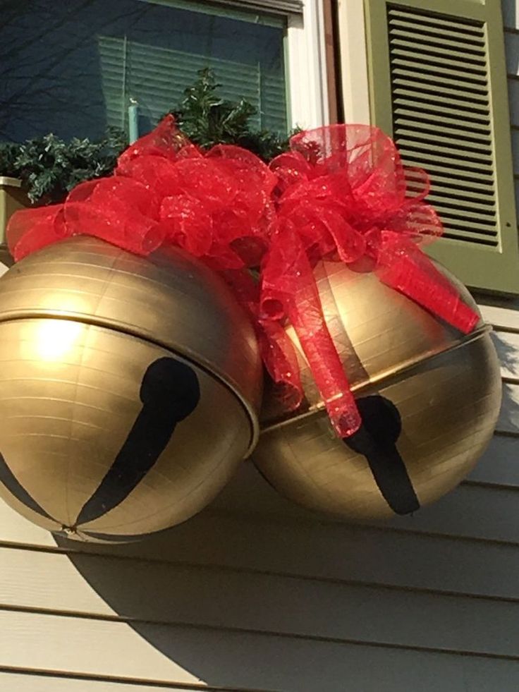 two bells with red bows are on the side of a house