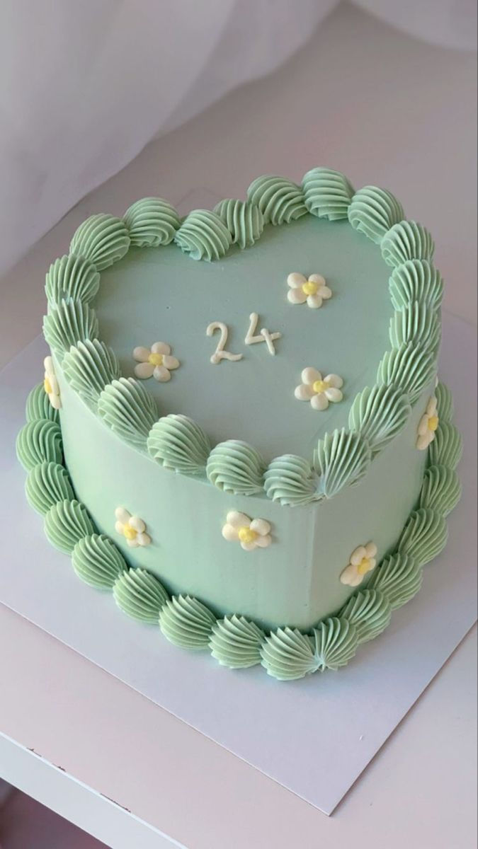 a heart shaped cake with the number twenty four on it's side and flowers in the middle