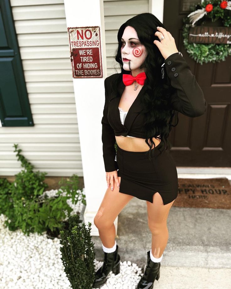 a woman dressed up as a creepy clown posing in front of a house for halloween