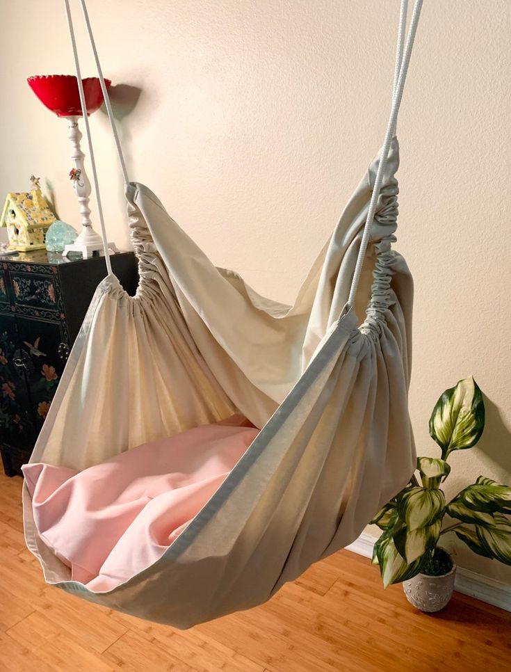 a hammock hanging from a wall next to a potted plant and wooden floor