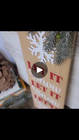 a wooden sign that says let it snow and some pine cones are on the table