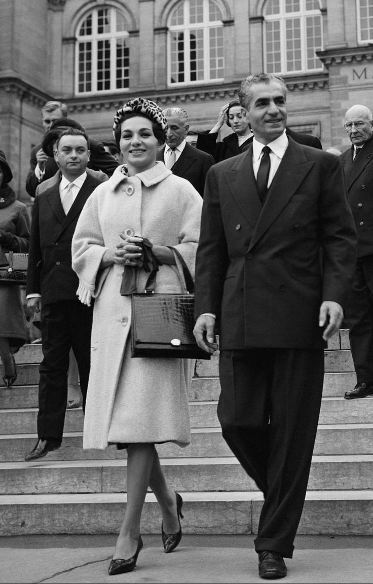 black and white photograph of man and woman walking down stairs with people in the background