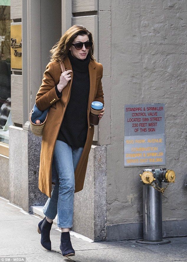 the woman is walking down the street with her coffee