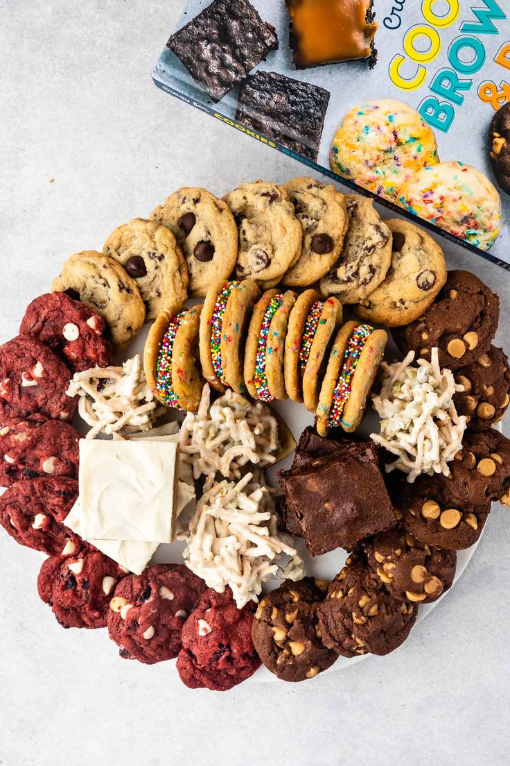 a plate full of cookies, chocolate chip cookies and sprinkles next to a cookbook