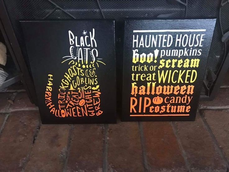 two black and orange halloween signs sitting on top of a brick floor next to a fireplace