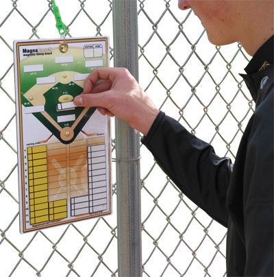 a man holding a clipboard with a baseball game on it next to a fence