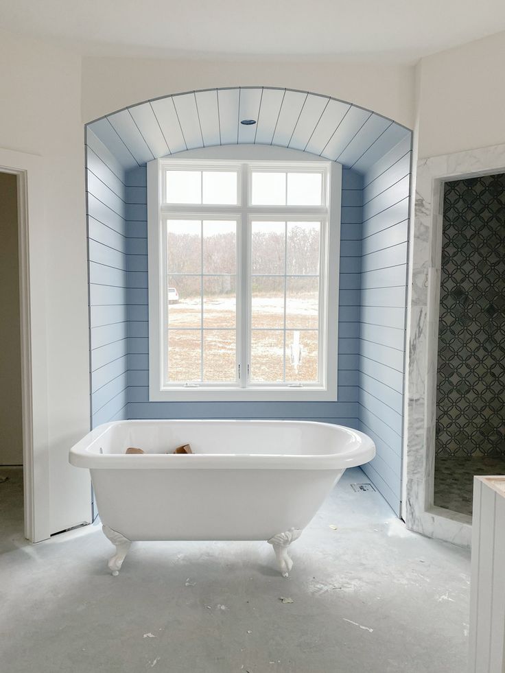 an empty bathroom with a claw foot bathtub and blue painted walls in the background