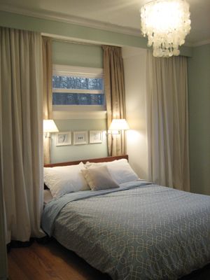 a bed sitting under a window in a bedroom next to two lamps on either side of the bed