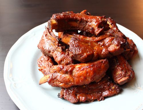 a white plate topped with meat on top of a wooden table