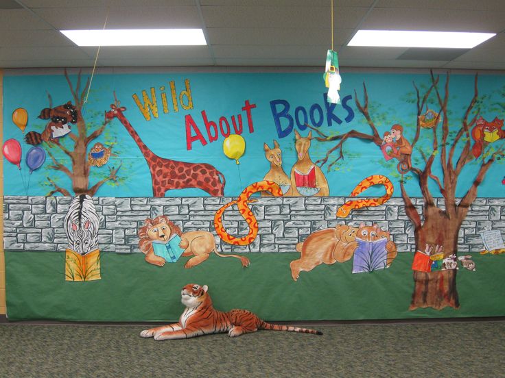 a tiger laying on the floor in front of a wall with books painted on it