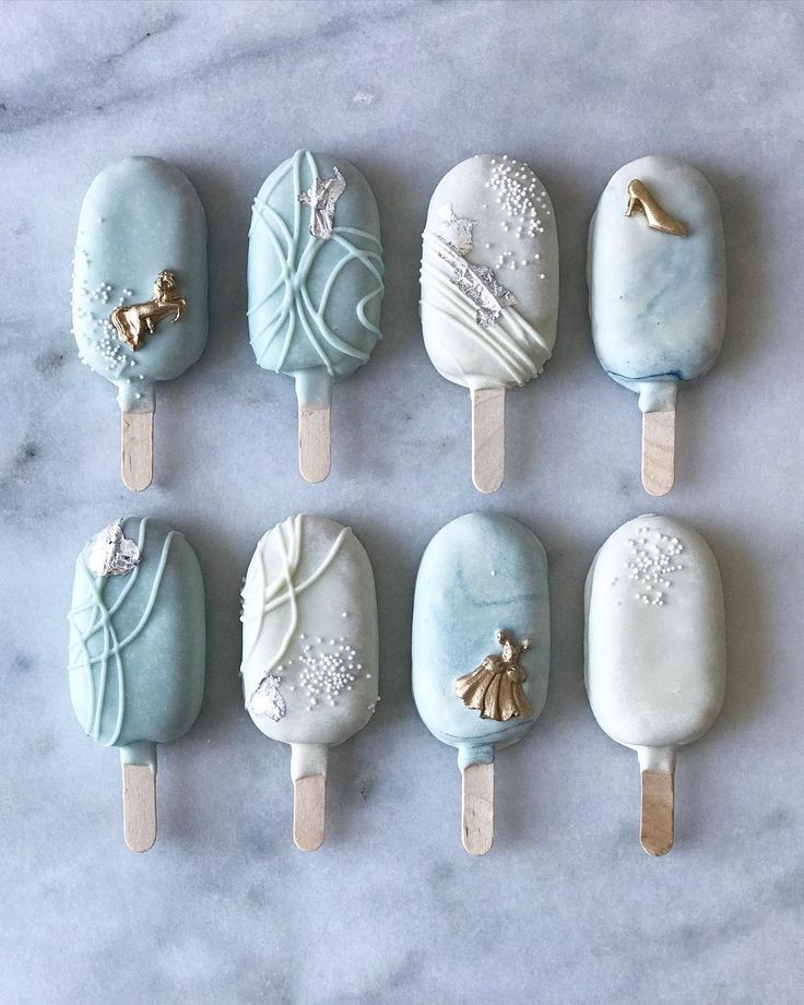 six ice cream lollipops are arranged on a marble countertop with gold and silver decorations