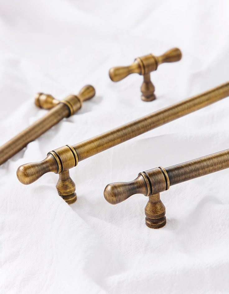 four antique brass handles and knobs on a white sheet