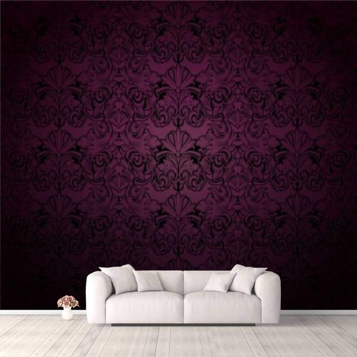 a white couch sitting in front of a wall with a purple and black pattern on it