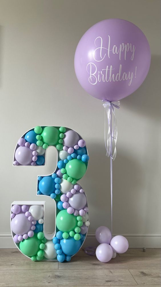 the number three is decorated with balloons and streamers