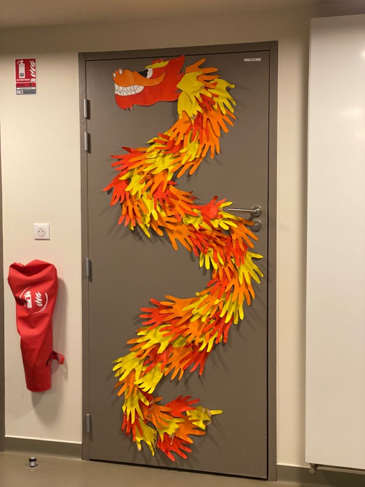 an orange and yellow fire hydrant sitting in front of a door decorated with leaves