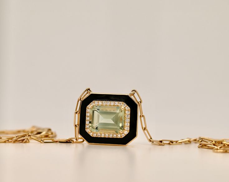 Art Déco style necklace set with an emerald cut green amethyst and 0.13ctw pave diamonds. Highlighted with black enamel. 14k Yellow Gold Green Amethyst: 2.22 cctw 32 Diamonds: 0.13ctw Black Enamel Adjustable 15”-16 1/2” Van Den Abeele Luxury Rectangular Gemstone Pendant Jewelry, Art Deco Yellow Gold Jewelry With Gemstone Accents, Luxury Emerald Cut Evening Jewelry, Fine Jewelry Diamond Necklace With Black Enamel, Fine Jewelry Black Enamel Necklace, Luxury Green Square Pendant Jewelry, Luxury Gemstone Square Pendant Jewelry, Fine Jewelry With Gemstone Accents For Evening, Luxury Square Pendant Gemstone Jewelry