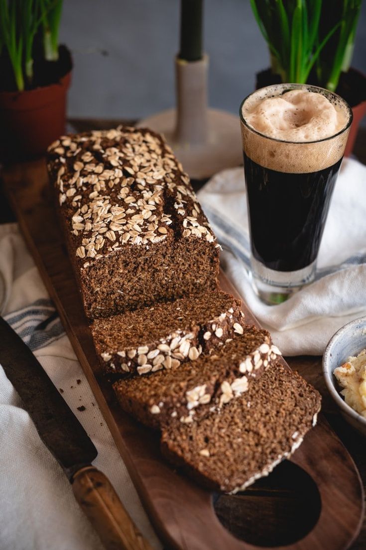 a loaf of bread sitting on top of a wooden cutting board next to a cup of coffee