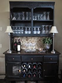 a black cabinet with wine glasses and bottles on it