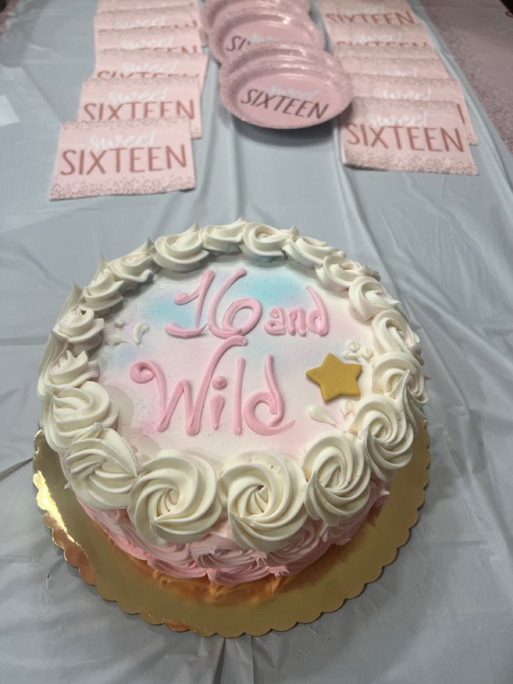 a birthday cake on a table with pink and white frosting