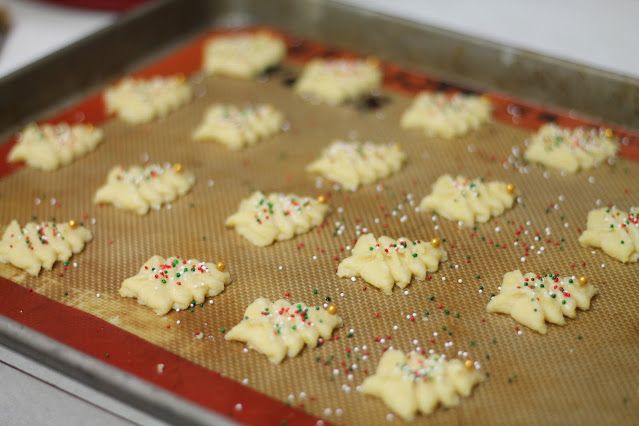 some cookies are on a cookie sheet and sprinkles are scattered around them