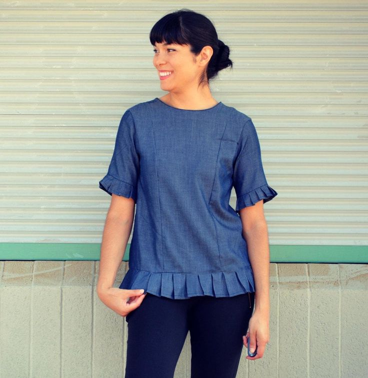 a woman standing in front of a building wearing black leggings and a blue top