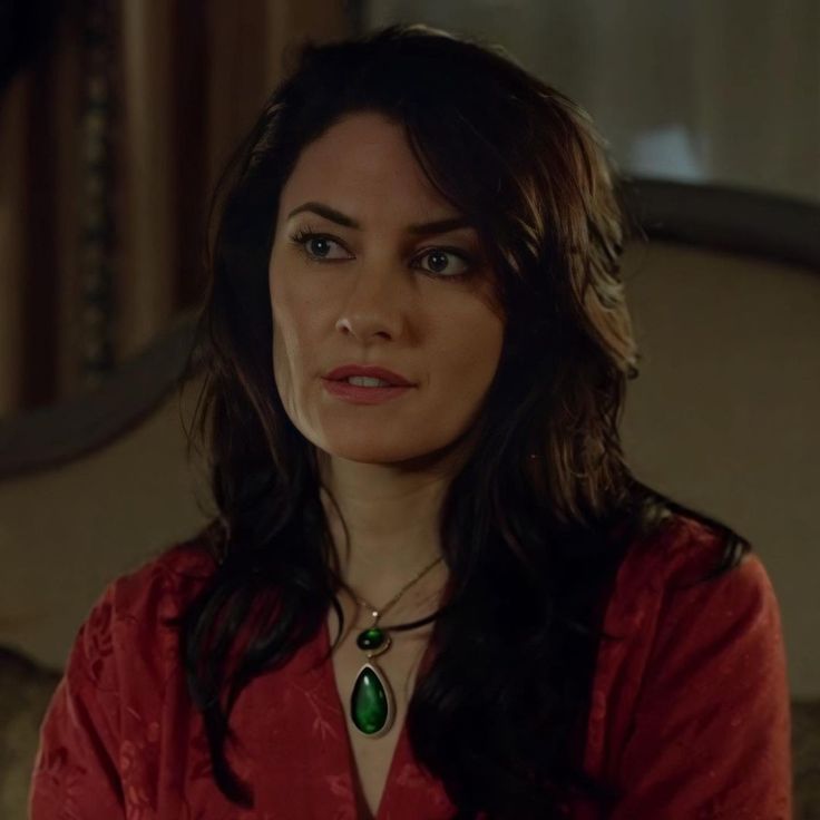 a woman wearing a red shirt and green necklace