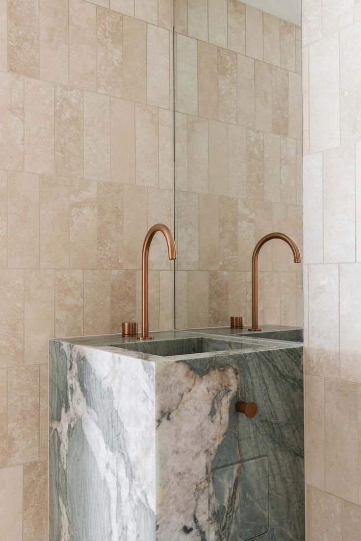 a marble sink with copper faucets in a bathroom