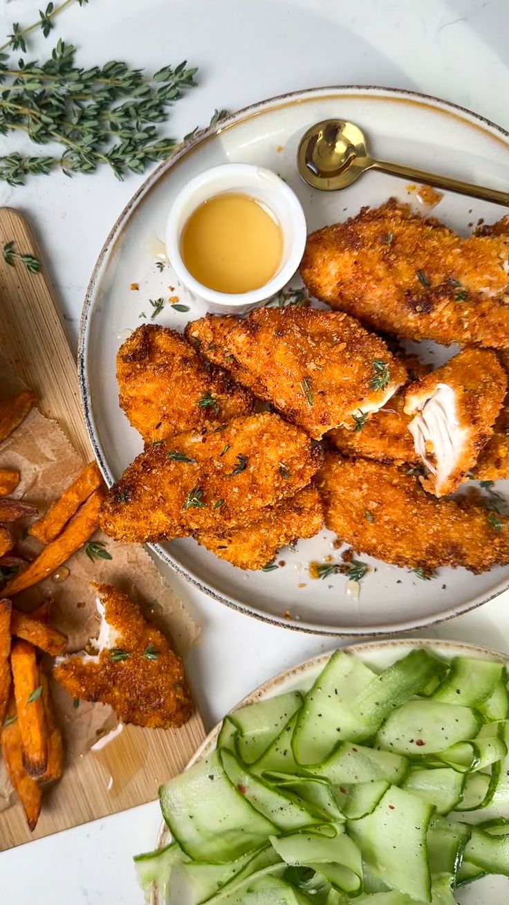 some fried food is on a plate with carrots and cucumbers next to it