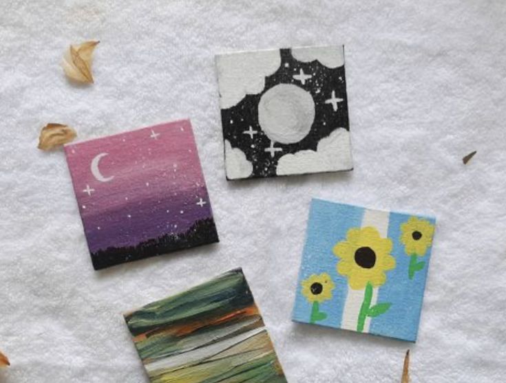 four small square magnets with flowers on them sitting on top of a white towel