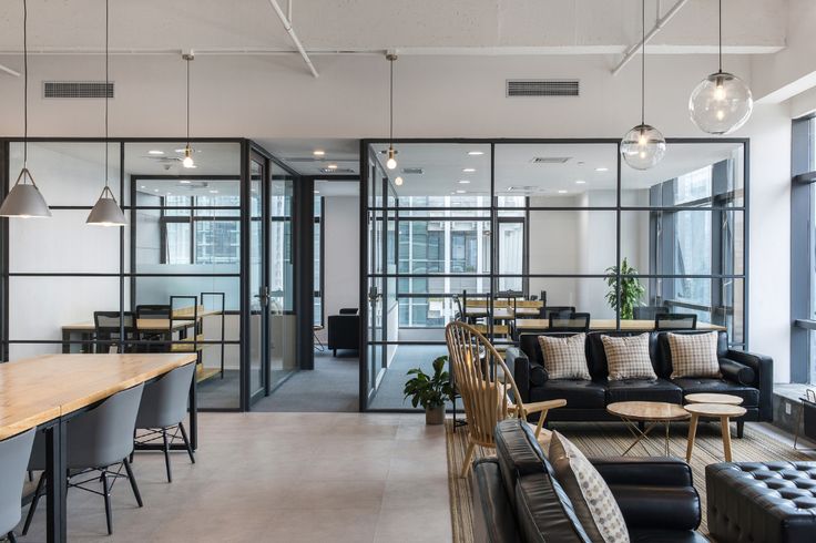 an office lobby with couches, chairs and tables in front of large windows that look out onto the city