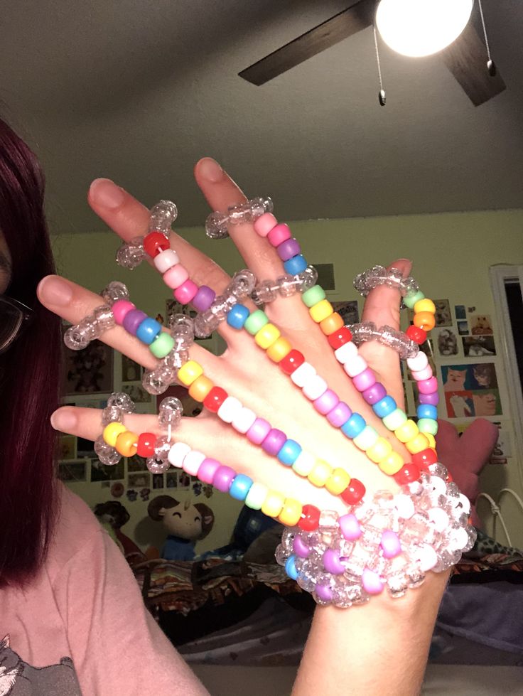 a woman with red hair is holding up her hand made out of plastic bracelets