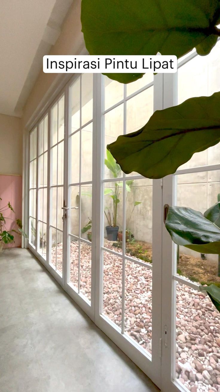 the inside of a room with large windows and plants in pots on either side of the window