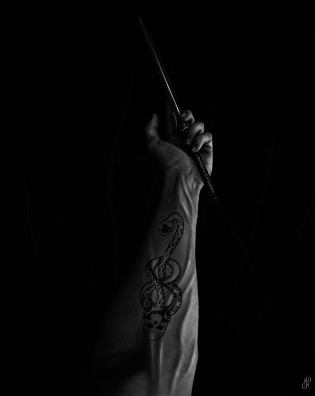 a person with a tattoo on their arm holding a wand in the air and pointing at something