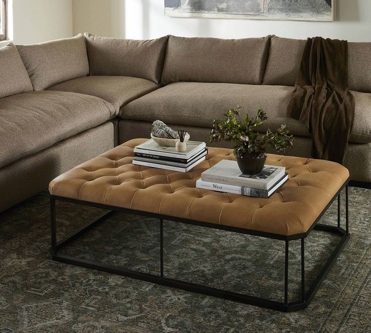 a living room with a sectional couch, coffee table and books on the end tables