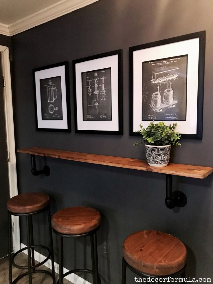 three framed pictures hang on the wall above bar stools