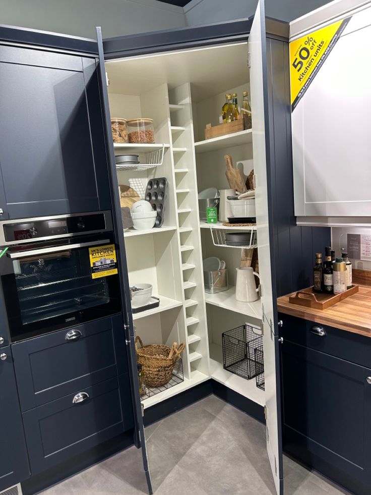 a kitchen with blue cabinets and white walls is shown in this image, there are baskets on the shelves next to the oven