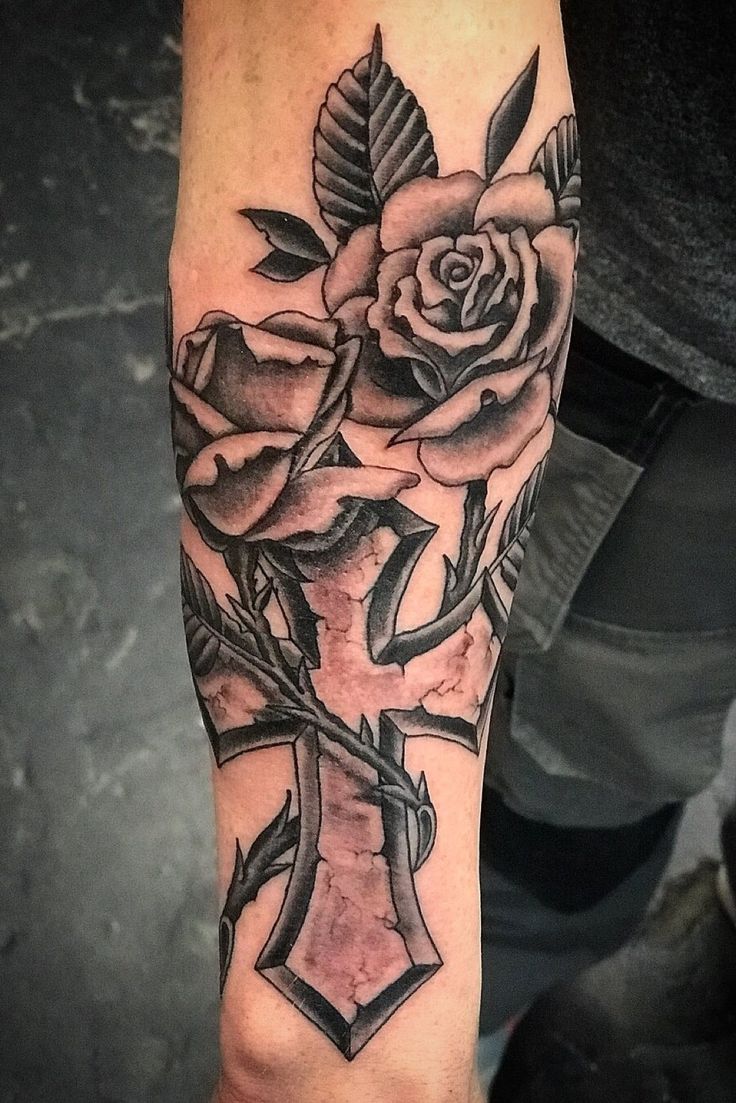 a person with a cross and roses tattoo on their arm